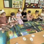 Grupa dziewczynek trzyma patyczki w ręku i nawija sznurek z myszkami.