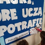 Dwoje dzieci przy tablicy rysuje kropki na skrzydłach.