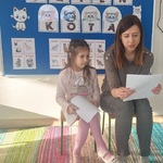 Mama Łucji czyta_ córka siedzi obok i trzyma rysunki. 