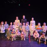 Dzieci i aktorzy stoją na scenie teatralnej.