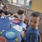 Chłopiec prezentuje kartkę z literką J_ wyklejoną zabarwioną solą.