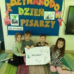Czworo dzieci trzyma plakat z napisem Skarżypyta.