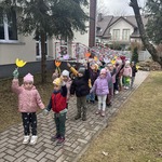 Dzieci z grupy drugiej stoją ustawione w parach_ trzymają wysoko papierowe tulipany_