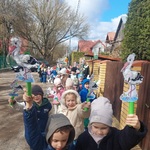 Dzieci z grupy czwartej stoją ustawione w parach_ w dłoniach trzymają papierowe bociany_