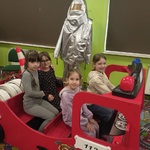Dziewczynki siedzą w drewnianym wozie strażackim.