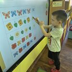 Chłopiec rozwiązuje rytmiczne zadanie na tablicy multimedialnej.
