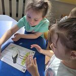 Dwie dziewczynki ułożyły na stoliku obrazek bociana.