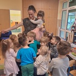 Pani trzyma na rękach dziecko_ inne dzieci się do niej przytulają_