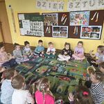 Dzieci siedzą w kręgu trzymając instrumenty.