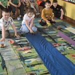 Dzieci puszczają samochody różnej wielkości na materiałach o różnej fakturze.