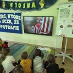 grupa dzieci ogląda film.
