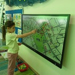 BOF 3 Dziewczynka stoi przy ekranie z wyświetloną mapą.jpg