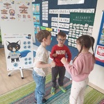 Dwóch chłopców i dziewczynka rozmawiają przy plakacie Bofka_