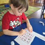 Chłopiec siedzi przy stoliku i nakleja elementy sudoku.