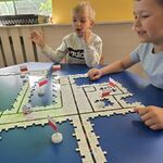 Dwóch chłopców obserwuje ozobota jadącego po trasie ułożonej z drewnianych puzzli.