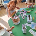 dziewczynki przy stoliku robią prace przestrzenne z makulatury.