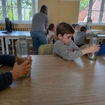 Dzieci wykonują doświadczenie z nurkiem zanużonym w zamkniętej butelce z wodą.