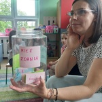 Nauczycielka trzyma w rękach pudełko, w tle dzieci 