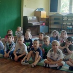 Dzieci siedzą na dywanie oglądają  edukacyjny