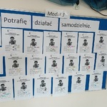 Tablica a napisem Potrafię działać samodzielnie_ na której wiszą karty pracy.