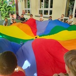 dzieci stoją w kole_ trzymają chustę animacyjną_ na chuście leży zabawka_ 