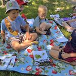 Chłopcy siedzą na kocu i prezentują kompozycje ułożone ze skarbów przyrody.