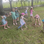 Dziewczynki na trawie kręcą hula-hop.
