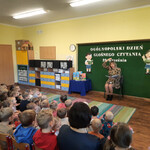 Pani przedstawia treść utworu_ siedząc naprzeciwko dzieci.