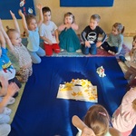 dzieci siedzą w małym kole na dywanie_ po środku leży otwarta książka -Kolorowy potwór.