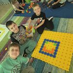 Trzech uśmiechniętych chłopców prezentuje uśmiech ułożony z korbo klocków.