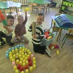 Troje uśmiechniętych dzieci prezentuje uśmiech ułożony z kolorowych kubeczków.