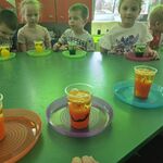 Dzieci siedzą przy stoliku i obserwują zmiany zachodzące w kubkach swoich i kolegów.