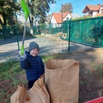 Chłopiec stoi za workiem, trzyma w górze łopatkę 