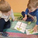 Dwaj chłopcy układają na dywanie puzzle.
