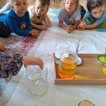 dzieci leżą na dywanie_ dziewczynka wlewa płyn do słoika.