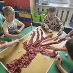 Grupa dzieci wykonuje z bibuły drzewo w zimowej szacie.