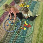 Dwie dziewczynki układają przedmioty w dwóch obręczach tak by powstała część wspólna.