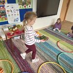 Dziewczynka niesie talerzyk z ogórkami do zielonej obręczy.