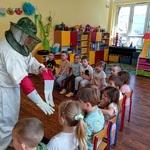 pszczelarz prezentuje dzieciom swoje ubranie ochronne