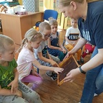 kobieta pokazuje dzieciom kratkę z miodem