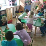dzieci w sali przedszkolnej rysujące przy stolikach