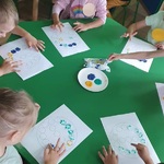 dzieci siedzące przy stoliku ze swoimi pracami z kropek