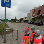 czworo dzieci w kamizelkach odblaskowych od znakiem parking dla rowerów