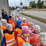 grupa dzieci w pomarańczowych kamizelkach w pobliżu ścieżki rowerowej