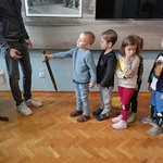 Dzieci ustawione w rzędzie kolejno biorą do ręki miecz rycerski 5.jpg