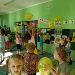 Grupa dzieci swobodnie tańczy w sali podrzucając żółte balony z narysowanymi uśmiechami 6.jpg