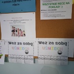 Na tablicy korkowej w szatni przedszkolnej przyczepione są kartki z napisem Weź ze sobą uśmiech  wraz z wyrywanką buźki 8.jpg
