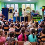 dzieci przedszkolne oglądające przedstawienie. Na scenie aktor i aktorka w przebraniu