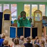 dzieci oglądające przedstawienie teatralne. Na scenie trzygłowy, zielony smok