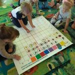 Dzieci układają na macie do kodowania obrazki z owocami wg kodu (rodzaj owocu, kolor ramki)